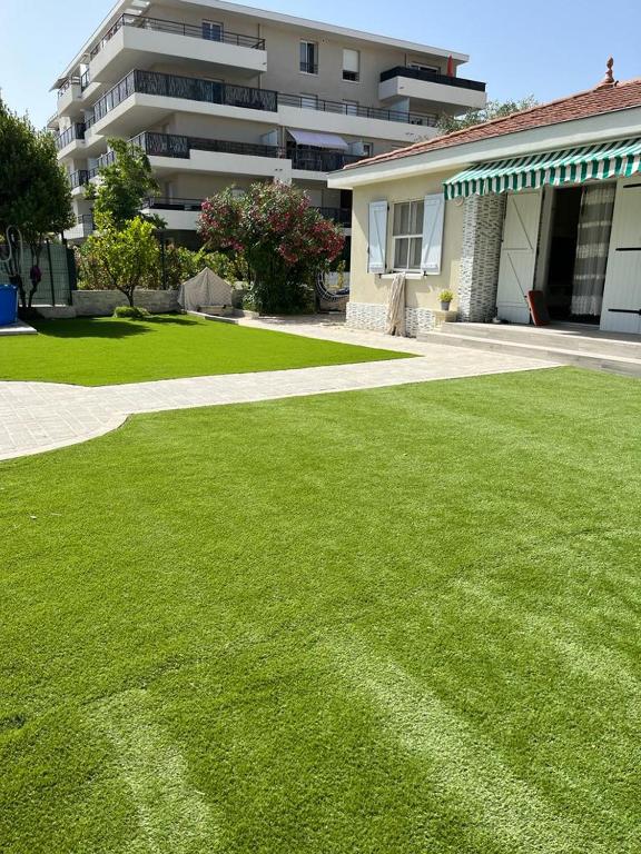 une cour d'herbe verte devant un bâtiment dans l'établissement VILLA MARCO POLO, à Cannes