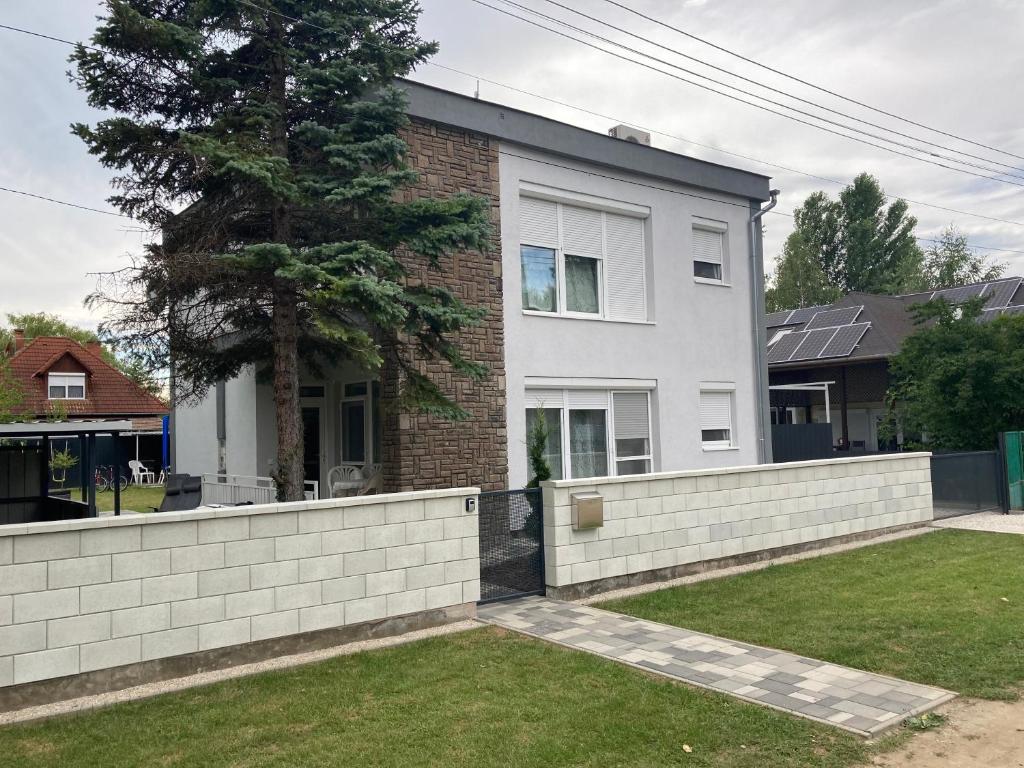 a house with a retaining wall and a fence at Révai Apartman Fonyód in Fonyód