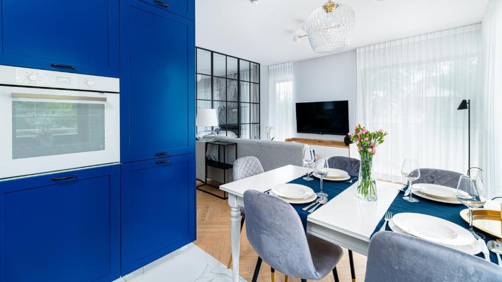 une salle à manger avec des armoires bleues et une table et des chaises blanches dans l'établissement Stone Hill Apartament Sunrise, à Szklarska Poręba