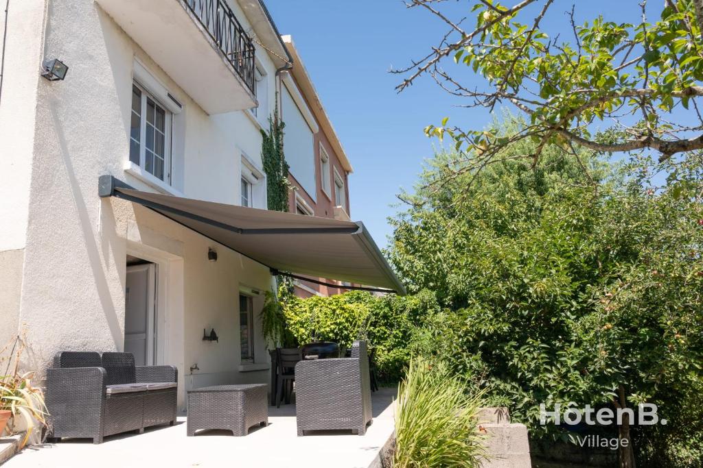 un patio avec des chaises et un auvent à côté d'un bâtiment dans l'établissement Large house close to city center Limoges, à Limoges