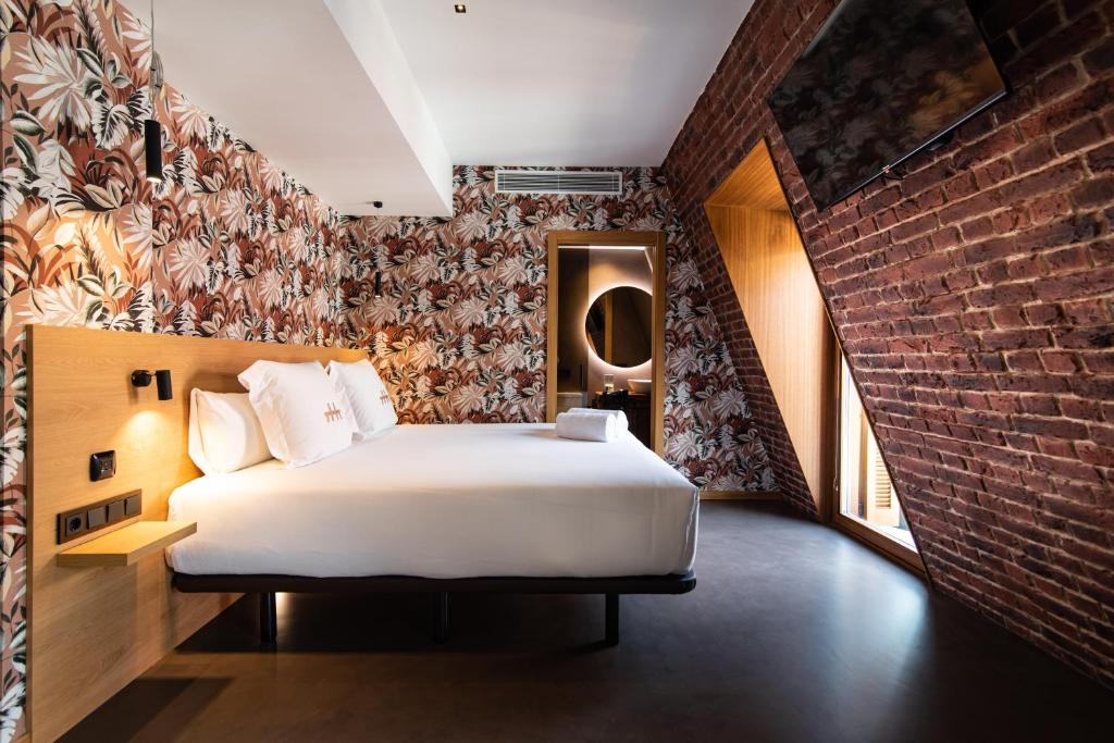 a bedroom with a bed and a brick wall at Hotel Atari in San Sebastián