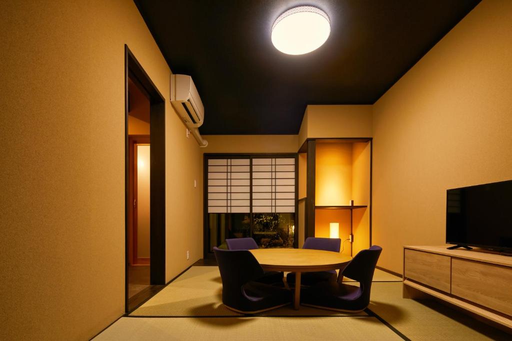 ein Esszimmer mit einem Tisch, Stühlen und einem TV in der Unterkunft TSUBOMI luxury Inn Shimabara Bettei 2 in Kyoto