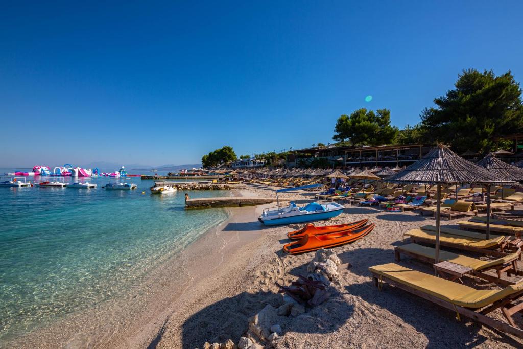 a beach with chairs and umbrellas and the water at Hotel New Crystal with Private Beach in Ksamil