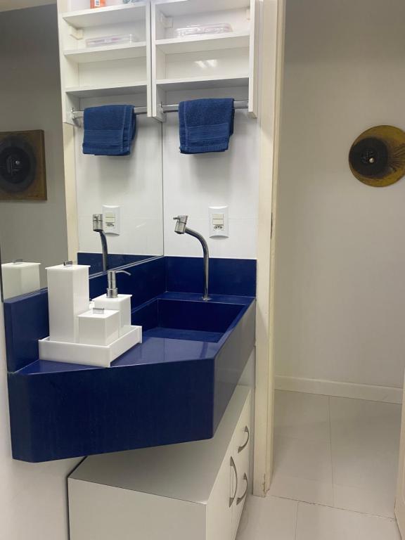 a bathroom with a blue sink and blue towels at Villagio em Bertioga in Bertioga