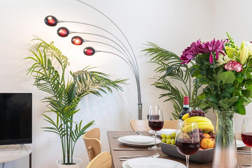 a dining room table with glasses of wine and flowers at The Great London Apartments in London