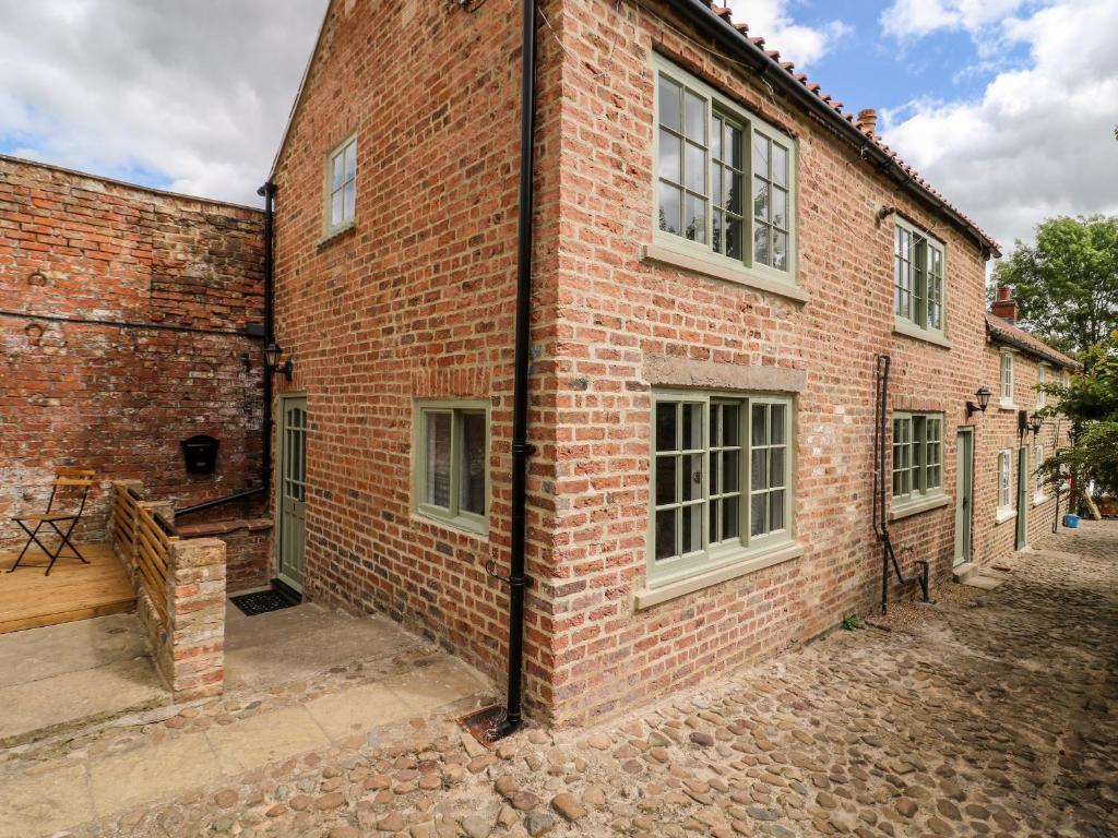 um edifício de tijolos com uma porta e janelas em Kemps Yard Retreat em Thirsk