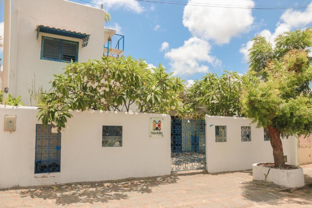 un bâtiment blanc avec un arbre devant lui dans l'établissement Hostel Republika, à Natal