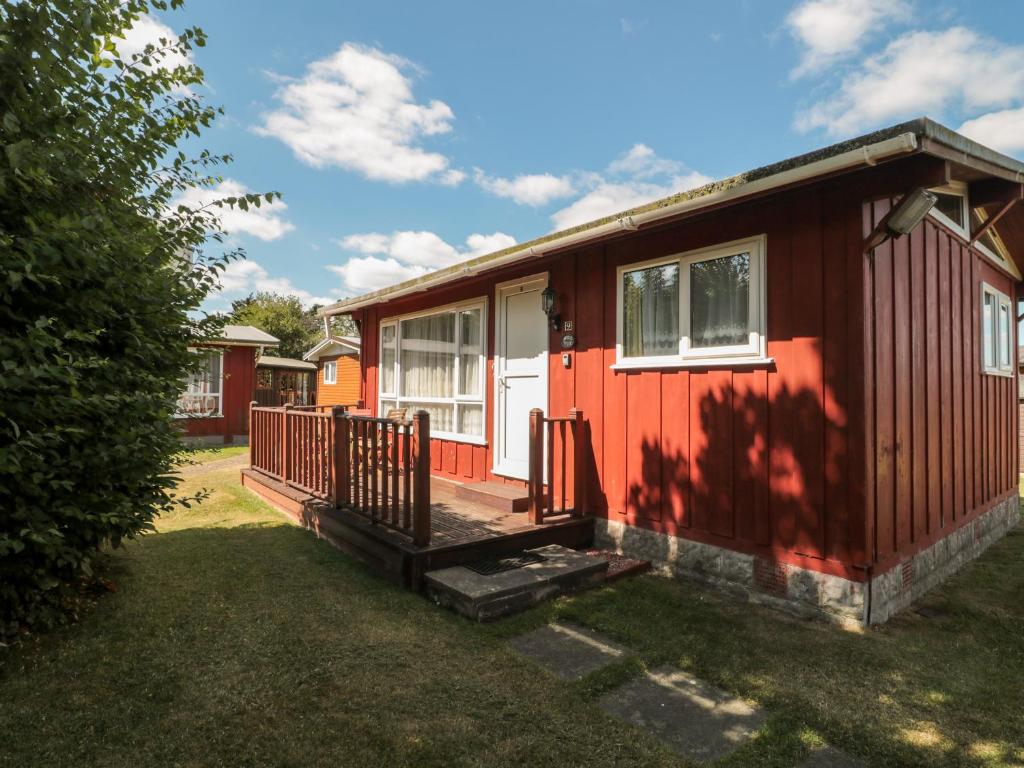 a red tiny house with a porch and a yard at Hill Top in Seaton