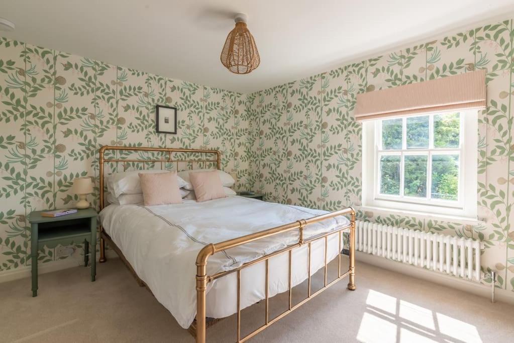 una camera da letto con un letto con carta da parati verde e bianca di The Cottage in the Clouds a Marlborough