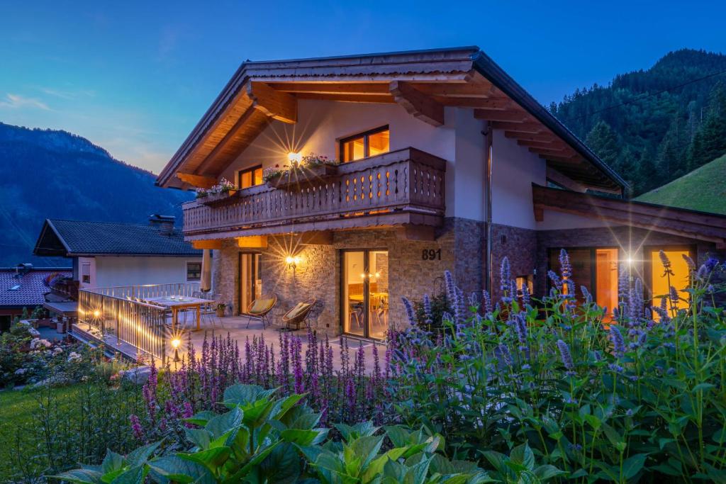 une maison avec un balcon et des fleurs violettes dans l'établissement Chalet Alpendomizil Ahorn, à Mayrhofen