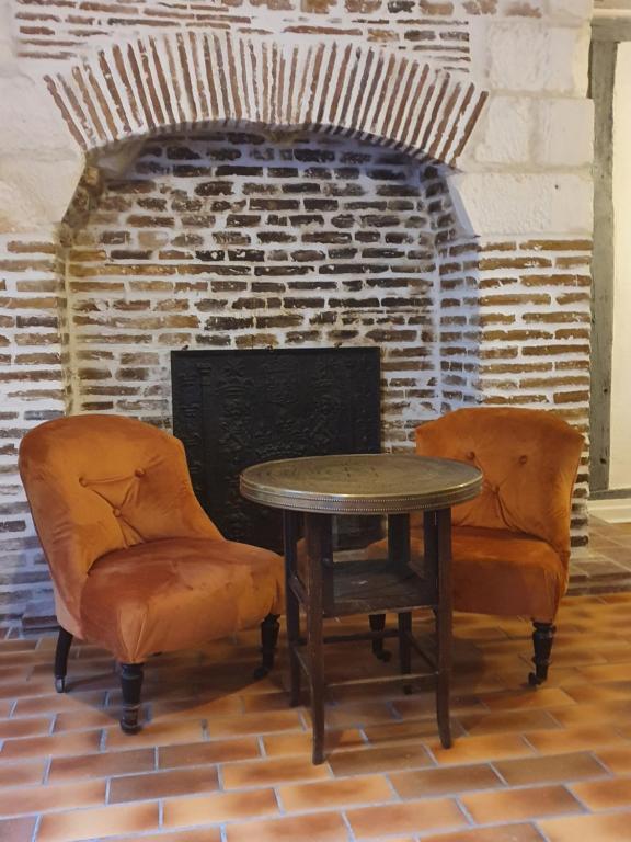 stół i dwa krzesła przed ceglanym kominkiem w obiekcie Le logis du clocher w Troyes