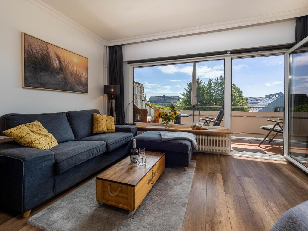 ein Wohnzimmer mit einem blauen Sofa und einem Tisch in der Unterkunft Ferienwohnung Abendsonne in Wenningstedt-Braderup