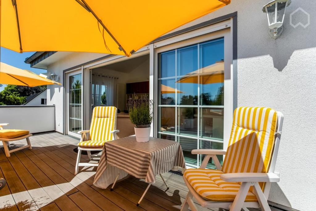 - une terrasse avec 2 chaises, une table et un parasol dans l'établissement Charmantes Loft Appartement, à Haan