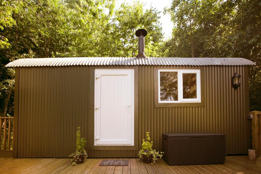 einem grünen Schuppen mit einer weißen Tür auf dem Deck in der Unterkunft Riverwood Farms Shepherds Hut in Talaton