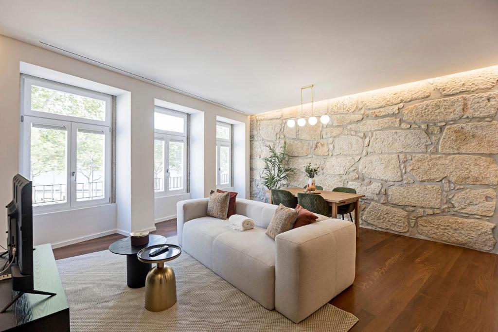 - un salon avec un canapé et un mur en pierre dans l'établissement Wonderful 2BR Duplex Near River by LovelyStay, à Porto