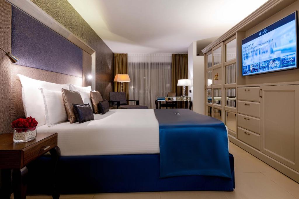 a hotel room with a large bed and a tv at AX The Palace in Sliema