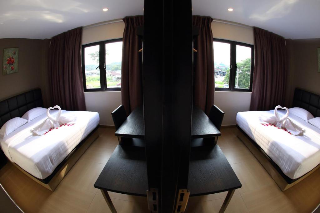 a hotel room with two beds and two windows at GL Hotel Kluang in Kluang