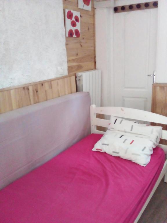 1 dormitorio con 1 cama con manta rosa en LA CABANE, en Bellac