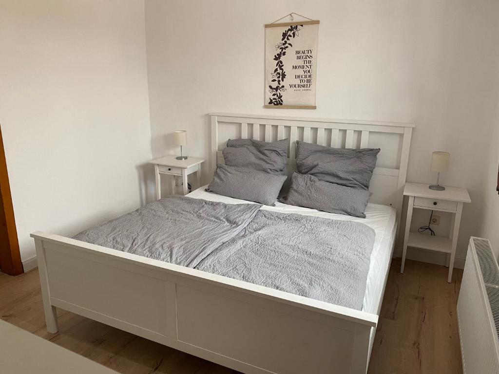 a white bed in a white room with two tables at Ferienhaus Pollerhof in Lindlar