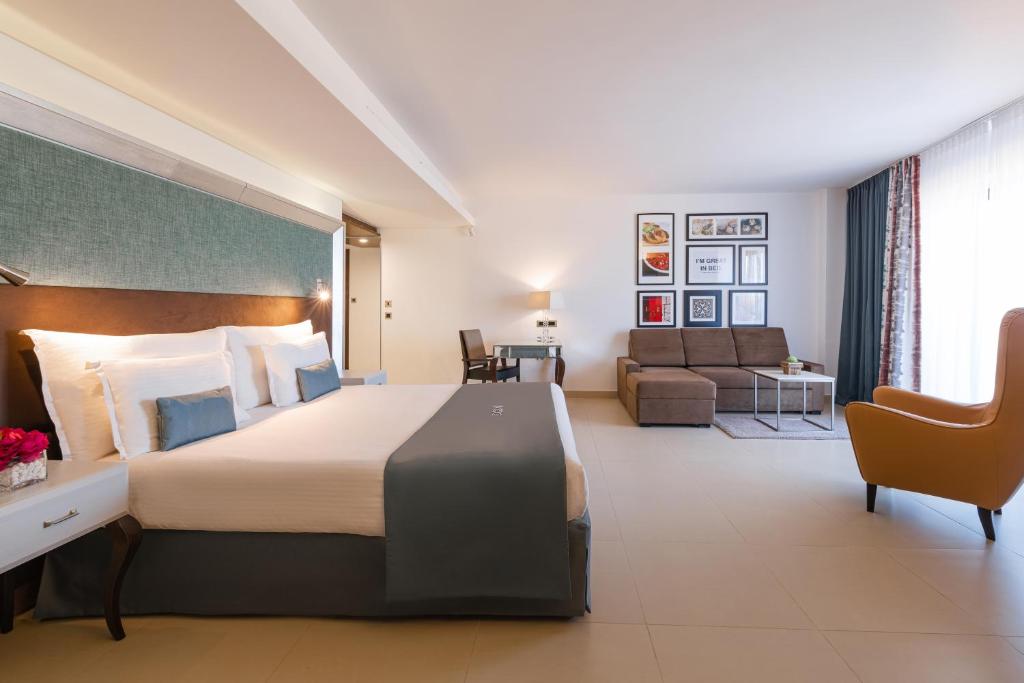 a hotel room with a large bed and a couch at AX The Palace in Sliema