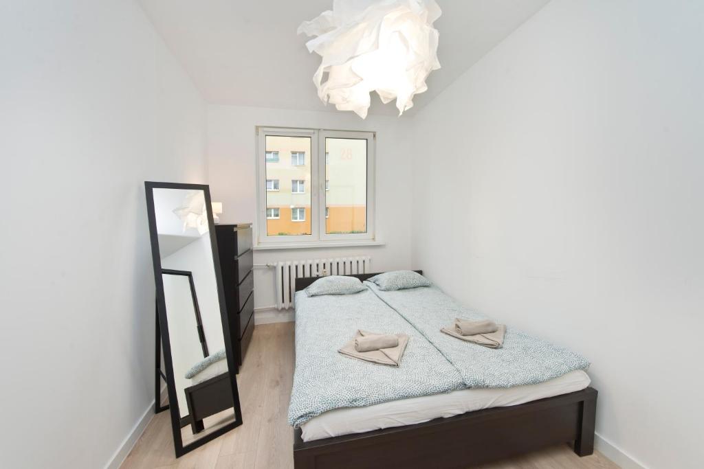 a bedroom with a bed and a mirror and a chandelier at YOURAPART Przymorze Piastowska in Gdańsk