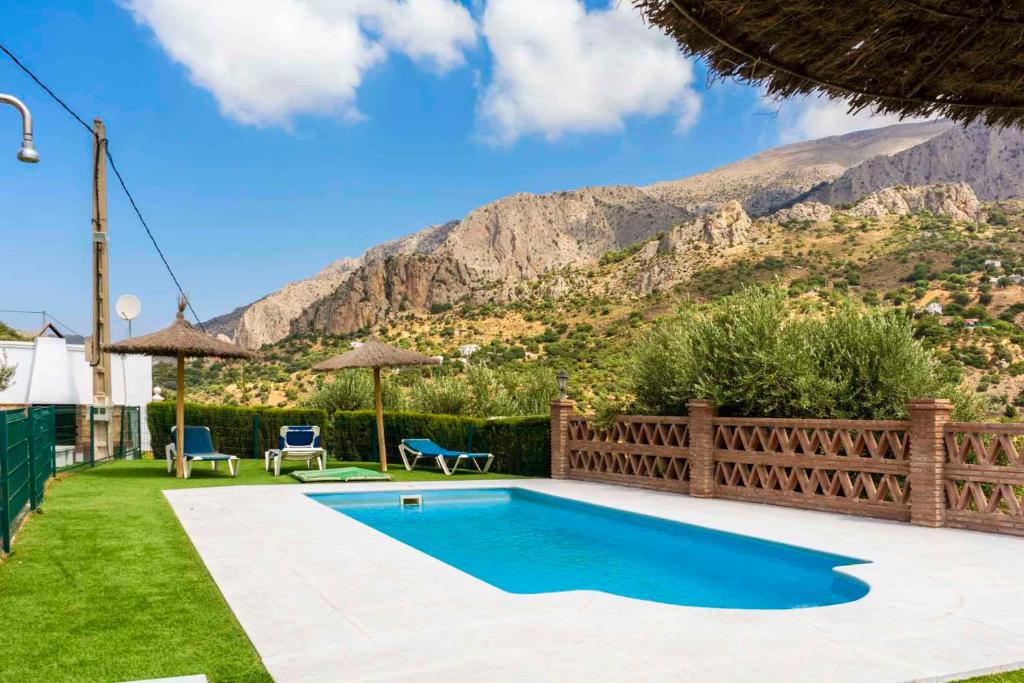 una piscina en un patio con montañas al fondo en Lagar del Chorro junto Caminito del Rey Piscina y Baloncesto en El Chorro