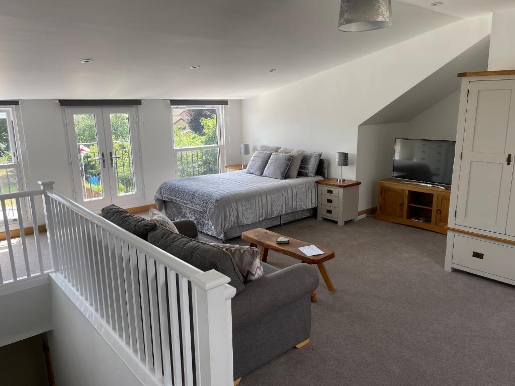 a bedroom with a bed and a couch and a television at Very Large lovely double room loft apartment in Carlton Colville