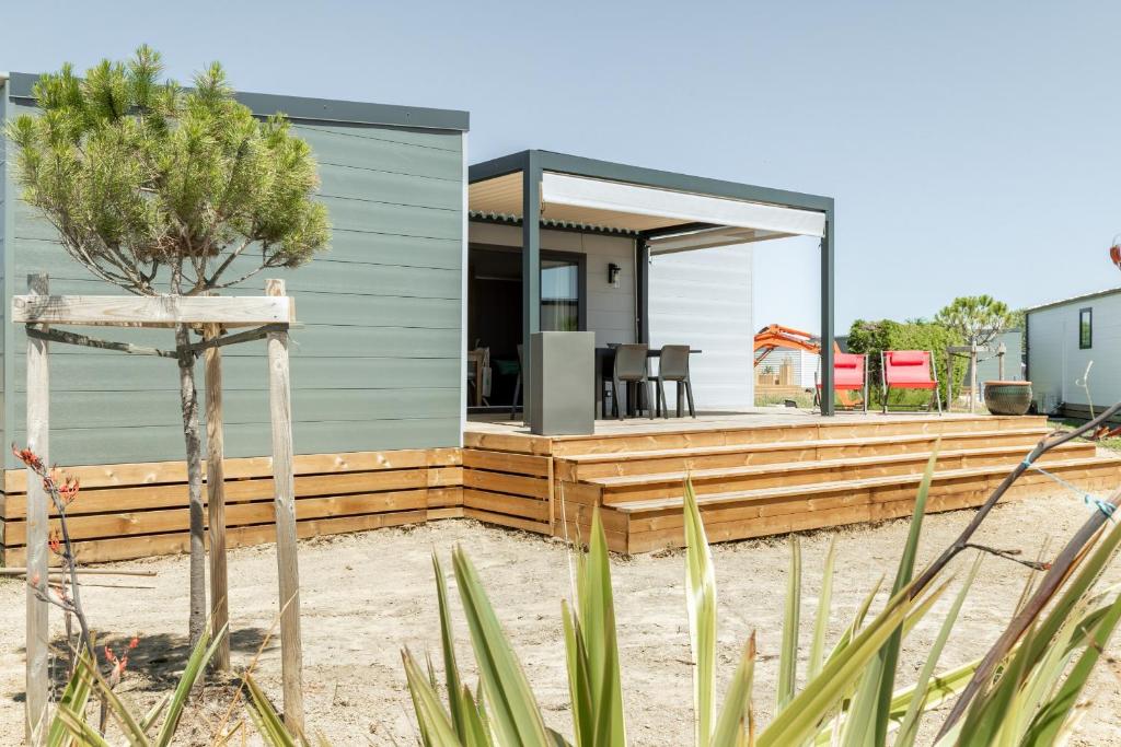 a house on the beach with a wooden deck at Chalet pour 4 dans une residence avec piscine couverte in Brétignolles-sur-Mer