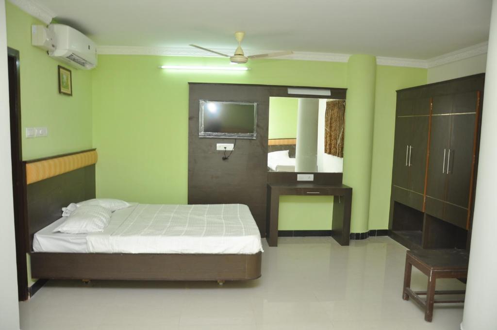a bedroom with a bed and a desk and a mirror at Jeyam Residency, Kumbakonam in Kumbakonam