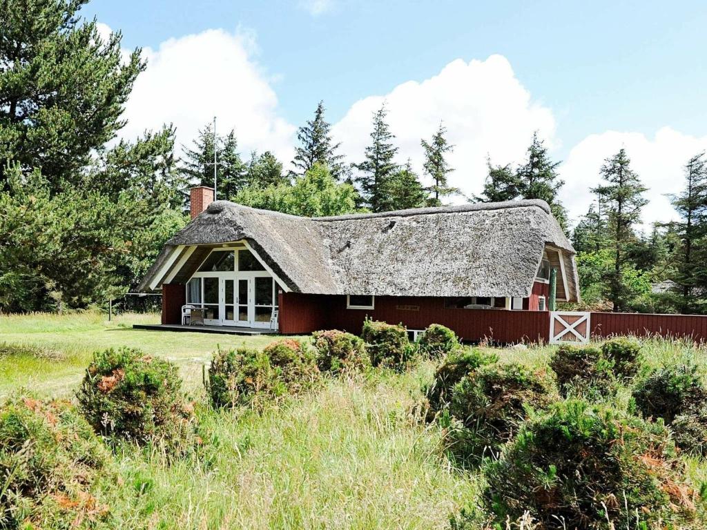 une maison rouge avec un toit gris dans un champ dans l'établissement 6 person holiday home in Bl vand, à Blåvand