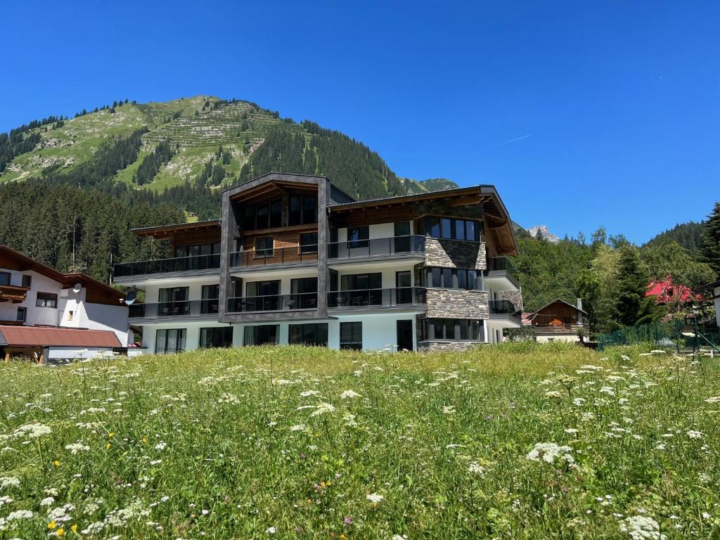 a building on a hill with a field of flowers at Apart Lech in Holzgau