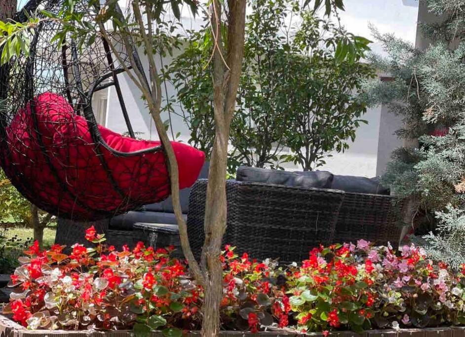 a red hammock sitting in a garden with flowers at Blue Garden Villa, Gjiri i Lalezit in Durrës