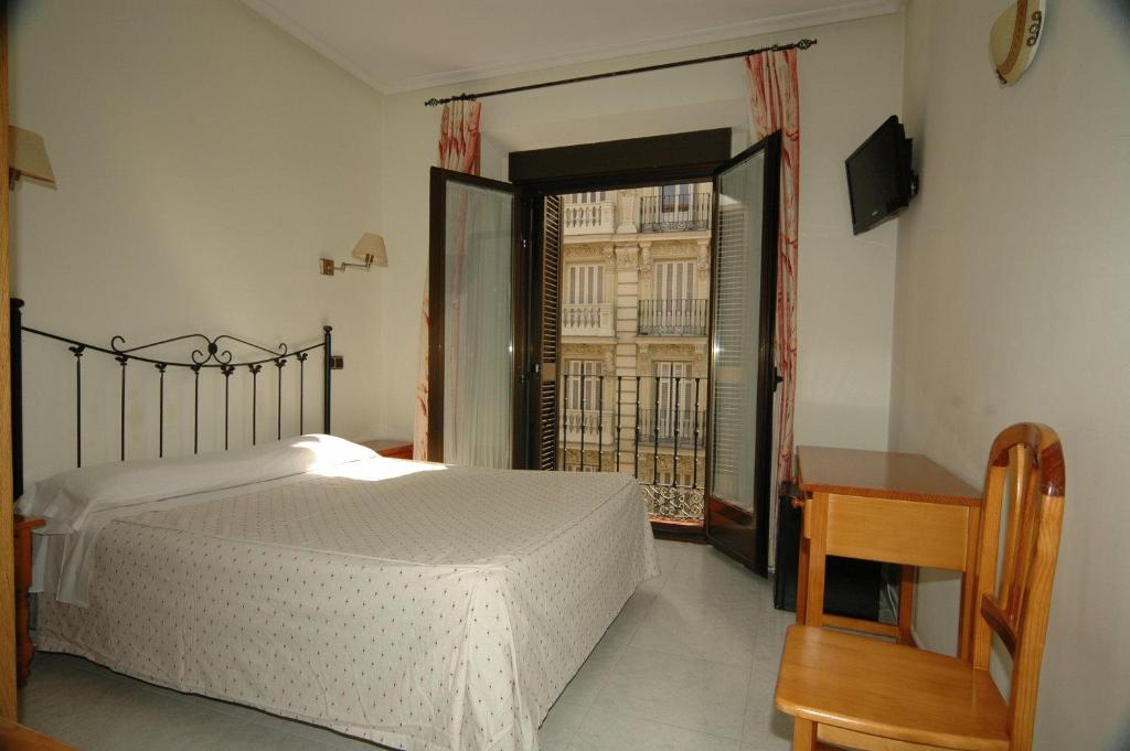 a bedroom with a bed and a desk and a window at Hostal Ivor in Madrid