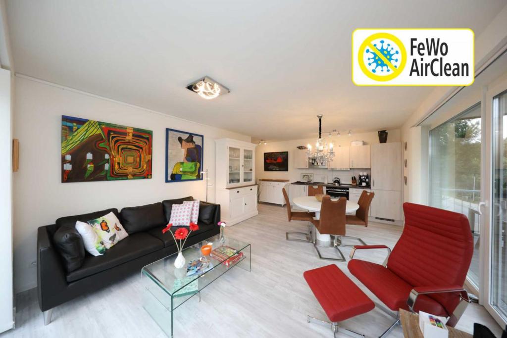 ein Wohnzimmer mit einem schwarzen Sofa und roten Stühlen in der Unterkunft Quartier Hohe Geest 15 - Nordseebrise - a69852 in Cuxhaven