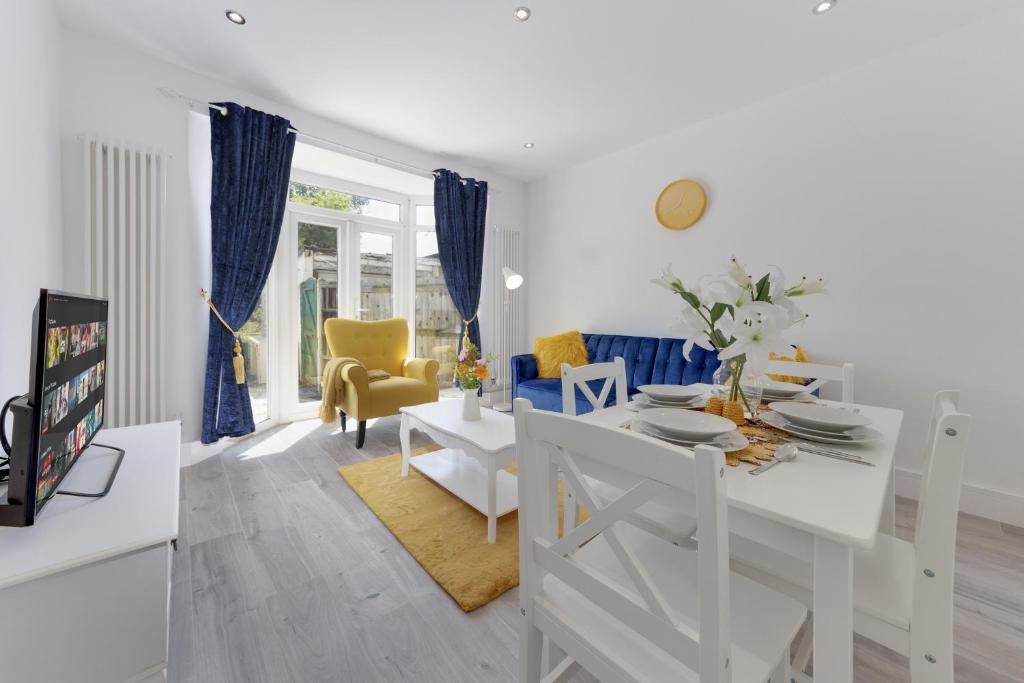 una sala de estar blanca con mesa blanca y sillas en Flourish Apartments - Marlborough House - Ilford en Redbridge