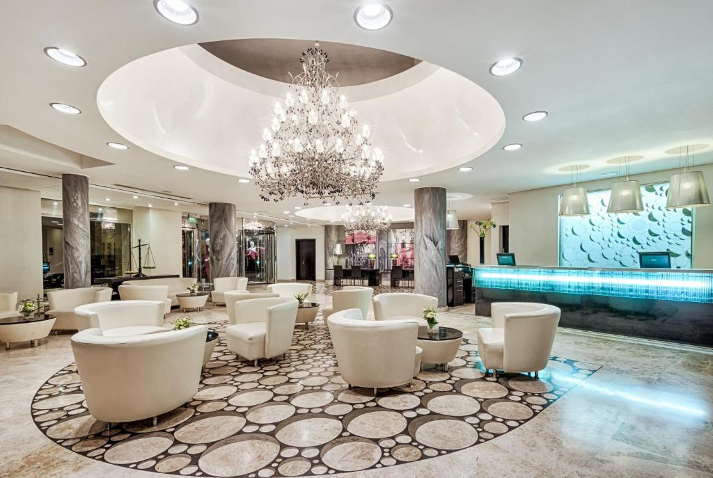 a large lobby with white chairs and a chandelier at AX The Palace in Sliema