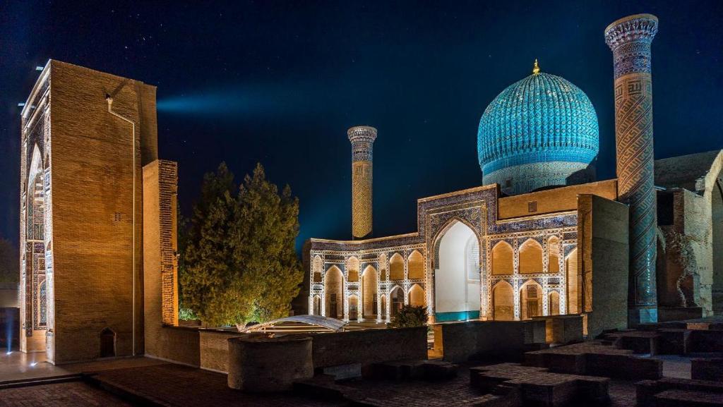 a mosque with a blue domed building at night at AMIRSHOX GUEST HOUSE in Samarkand