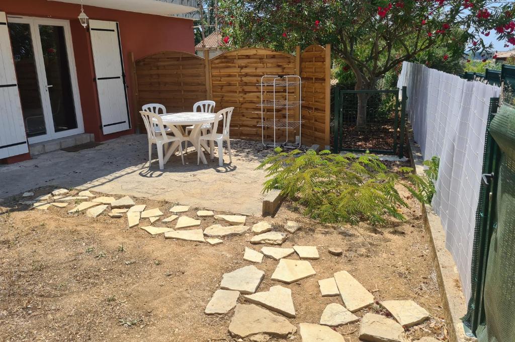 un patio avec une table et des chaises et une clôture dans l'établissement L' Escale des Îles en rdc de villa avec jardin à 5mn des plages et de toutes les commodités, à Six-Fours-les-Plages