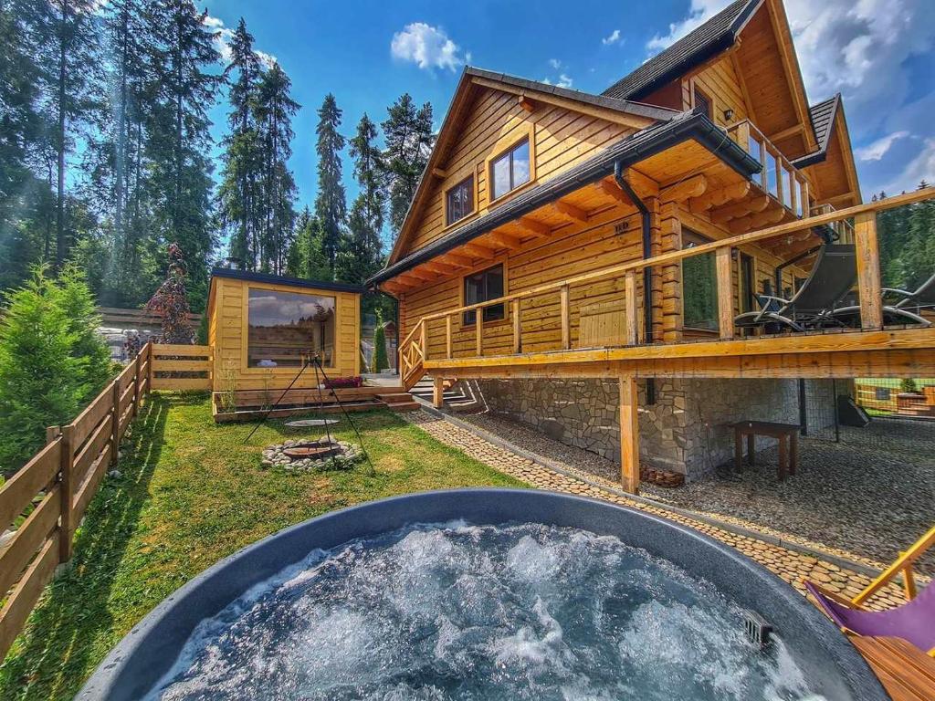 ワプシェ・ニジネにあるLK Resort Łapsze domy z prywatną balią i saunąの庭にホットタブ付きのログハウスです。