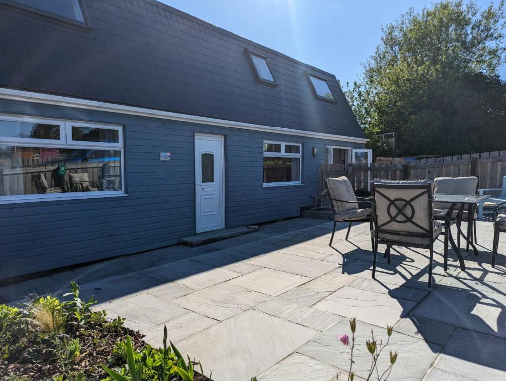 a patio with chairs and a table in front of a house at Coach House Cottage in Runswick