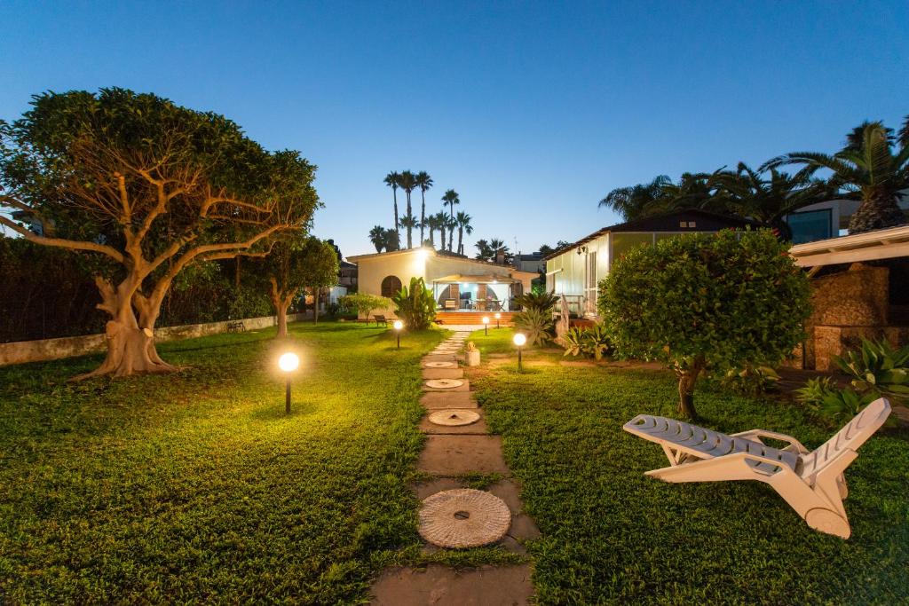 einen Garten mit einer Bank und Lichtern im Gras in der Unterkunft Villa Mary in Fontane Bianche