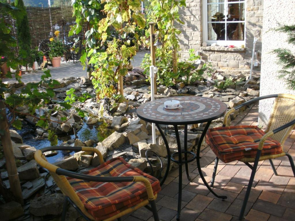 a patio with a table and chairs in a garden at Ferienweingut Benedikt Nilles in Pünderich