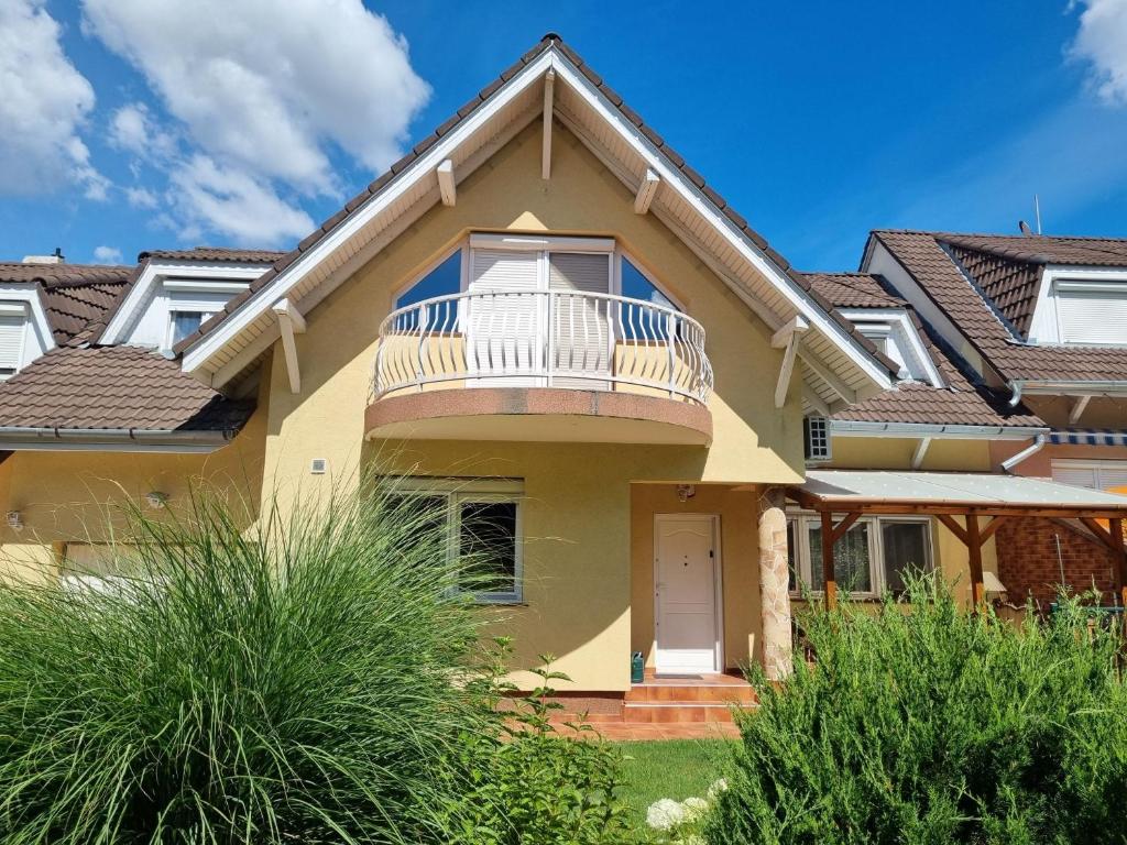 a yellow house with a balcony and bushes at Teresa Guest House in Csömör