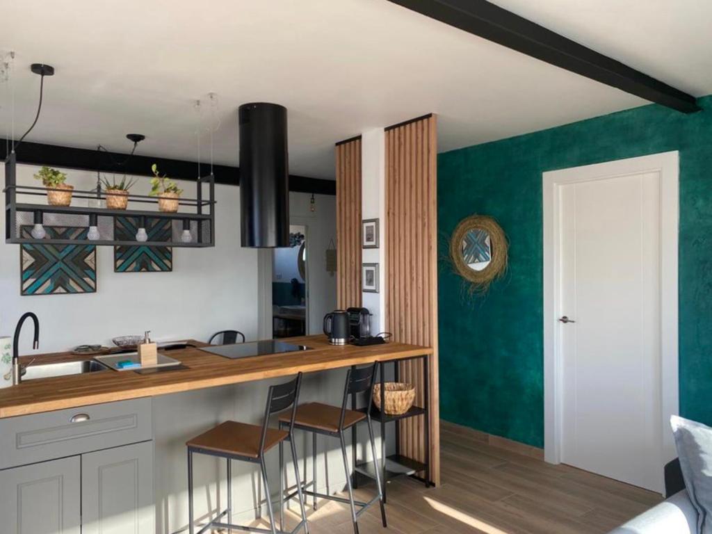 a kitchen with green walls and a counter with stools at SunPola Penthouse in Santa Pola