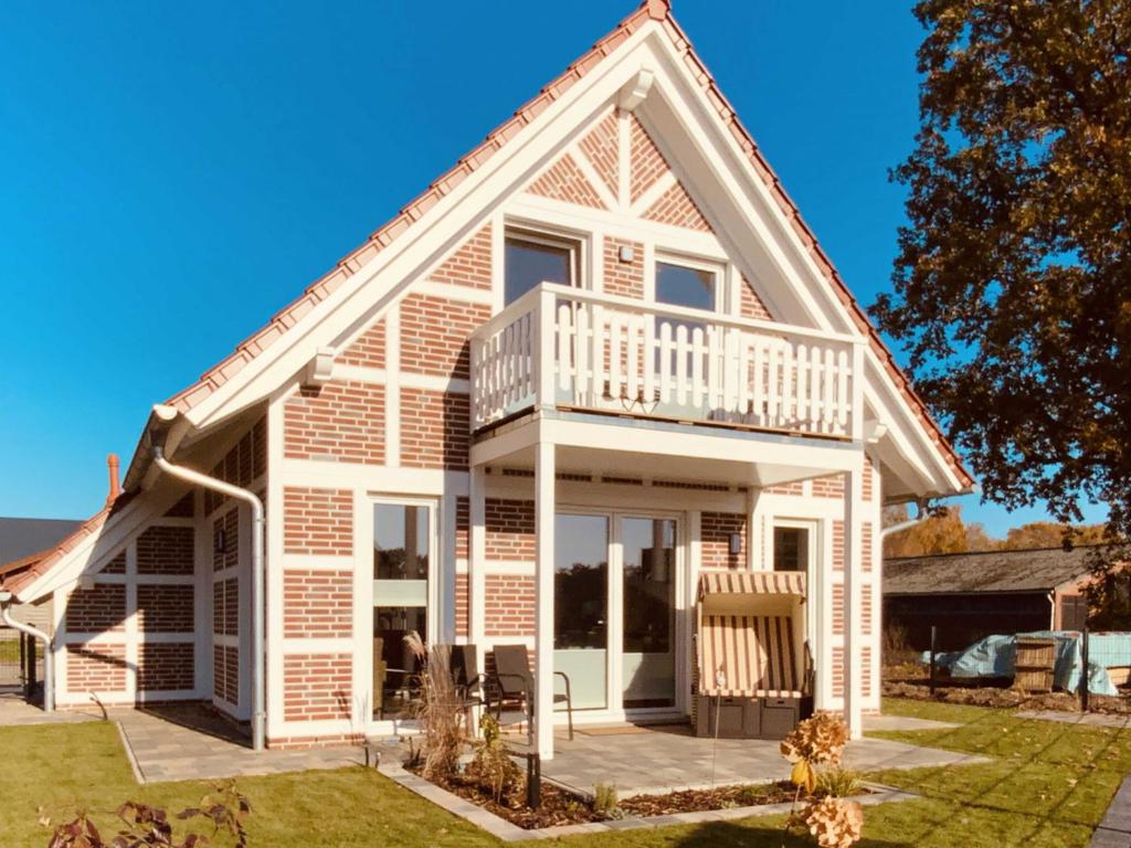 a white house with a porch and a balcony at Ferienhaus De Beers Huus - Holte-Spangen - a69919 in Cuxhaven