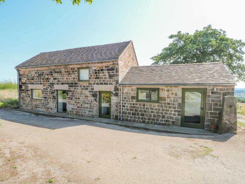 an old brick building with windows in a field at The Barn at Chatsworth Farm in Leek