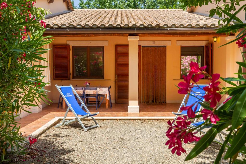 uma casa com duas cadeiras de jardim azuis e uma mesa em Trilo Begonia em Marina di Grosseto
