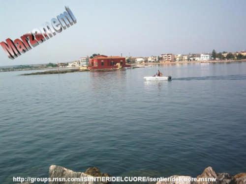 un petit bateau blanc dans une grande étendue d'eau dans l'établissement Suliccenti Marzamemi, à Marzamemi