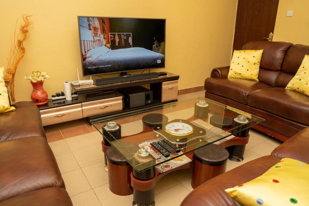ein Wohnzimmer mit Ledersofas und einem TV in der Unterkunft Bonaventure Apartment in Kisumu