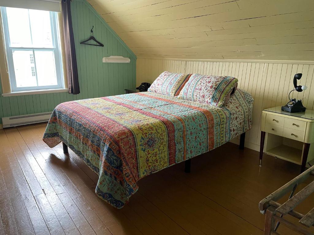 a bedroom with a bed with a quilt and a window at À la croisée des sommets in Notre-Dame-Des-Bois